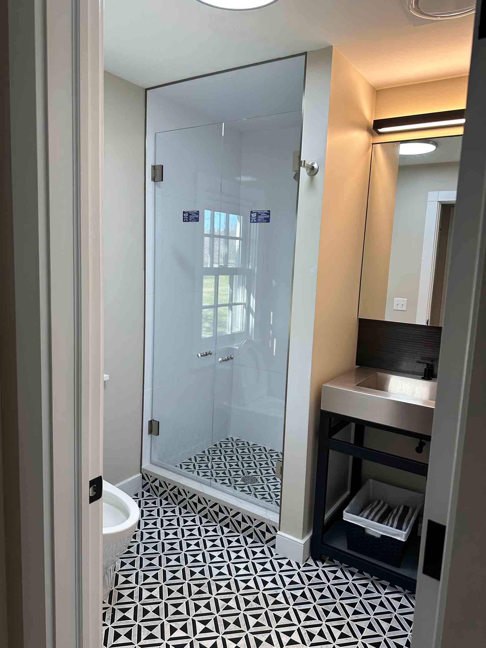 Custom bathroom by VF Builders with tile floor and glass shower with modern vanity and mirror