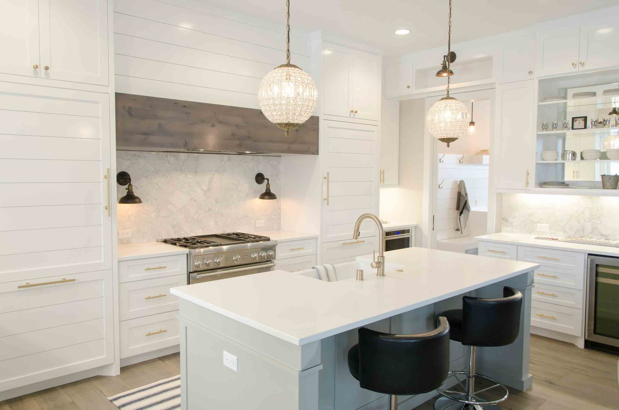 White kitchen with island, stools, range stove wall and base cabinets